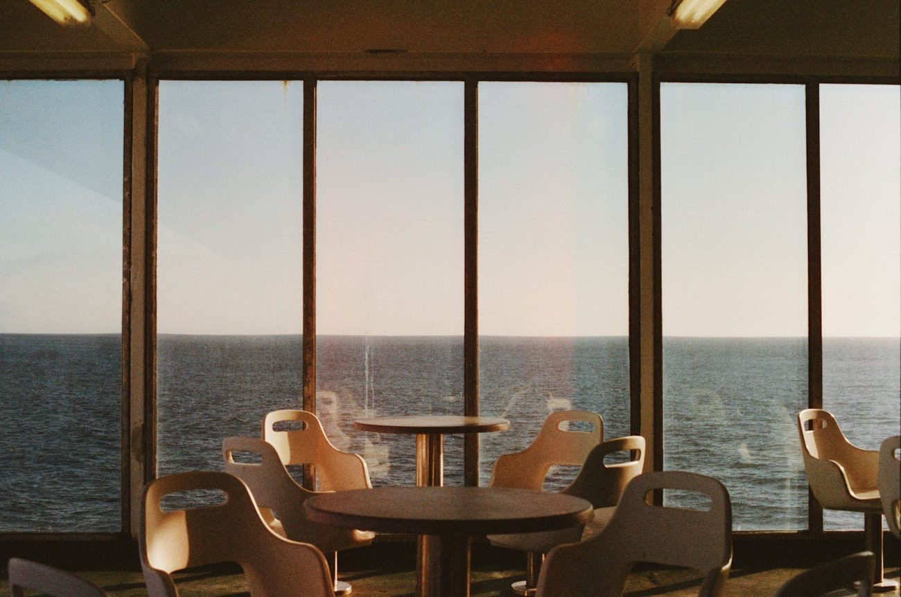 Empty cruise ship cafe with rows of chairs facing the sea — the reality behind the brochure dining photos